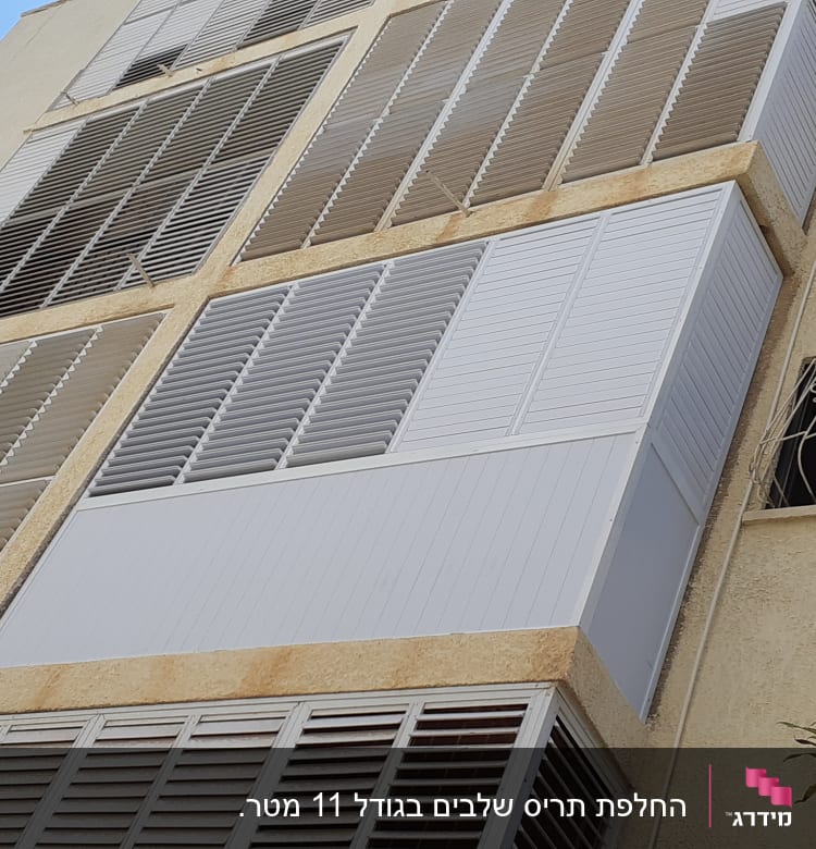 תריסי אלומיניום לבנים על קיר חיצוני של בניין